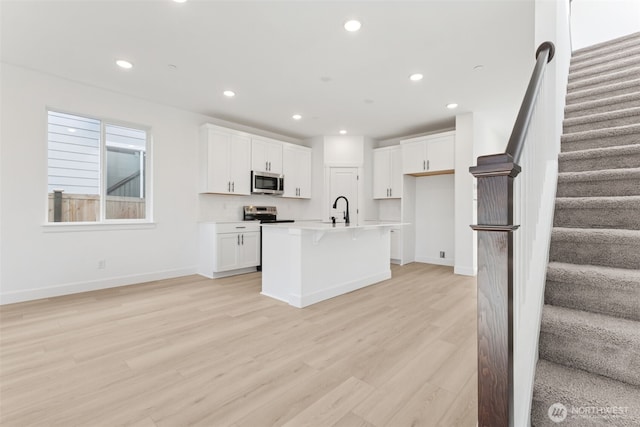 20620 97th Avenue St E Unit 16, Graham, WA 98338 - kitchen featuring stainless steel microwave, a sink, light wood-style flooring, recessed lighting, and white cabinets