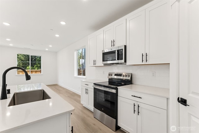 20620 97th Avenue St E Unit 16, Graham, WA 98338 - kitchen featuring stainless steel appliances, a sink, light wood-type flooring, tasteful backsplash, and light countertops