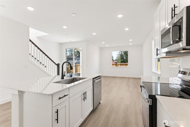 20620 97th Avenue St E Unit 16, Graham, WA 98338 - kitchen with stainless steel appliances, a sink, light wood-style flooring, a kitchen island with sink, and recessed lighting