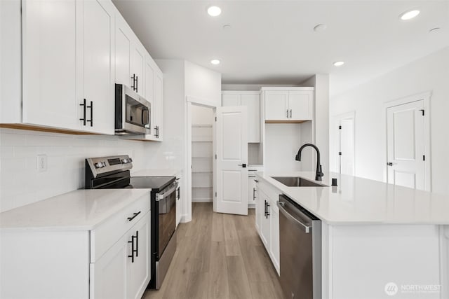 20620 97th Avenue St E Unit 16, Graham, WA 98338 - kitchen with appliances with stainless steel finishes, a sink, light wood-type flooring, an island with sink, and tasteful backsplash