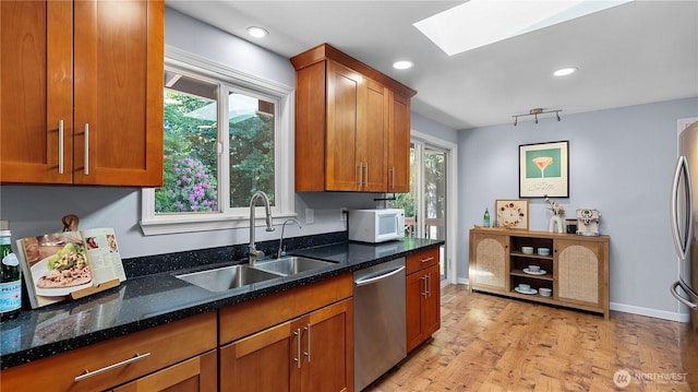 9824 NE 139th St, Kirkland, WA 98034 - kitchen featuring appliances with stainless steel finishes, a skylight, a sink, brown cabinetry, and light wood-style flooring
