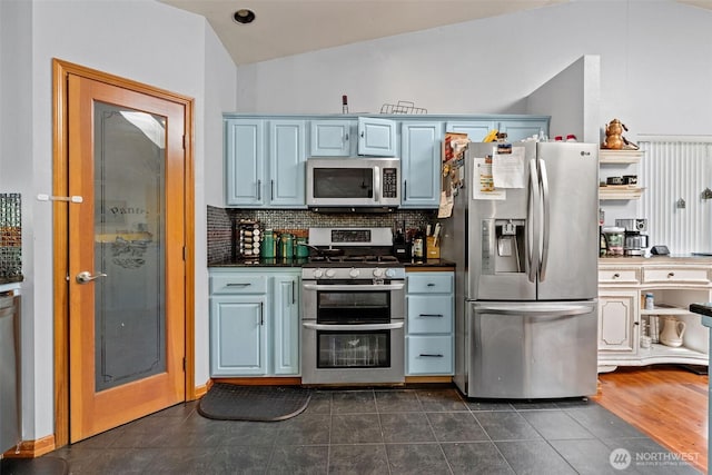6940 35th St W, University Place, WA 98466 - kitchen with appliances with stainless steel finishes, dark countertops, lofted ceiling, decorative backsplash, and dark tile patterned flooring