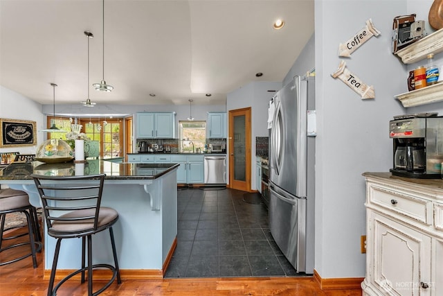 6940 35th St W, University Place, WA 98466 - kitchen featuring appliances with stainless steel finishes, dark countertops, blue cabinetry, a breakfast bar area, and a sink