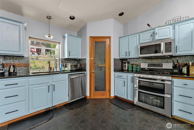 6940 35th St W, University Place, WA 98466 - kitchen with stainless steel appliances, a sink, dark countertops, backsplash, and vaulted ceiling