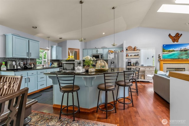 6940 35th St W, University Place, WA 98466 - kitchen with dark countertops, appliances with stainless steel finishes, a sink, backsplash, and a kitchen bar