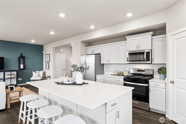 7318 281st Pl NW Unit 42, Stanwood, WA 98292 - kitchen featuring stainless steel appliances, a center island, a breakfast bar, dark wood-style floors, and light countertops