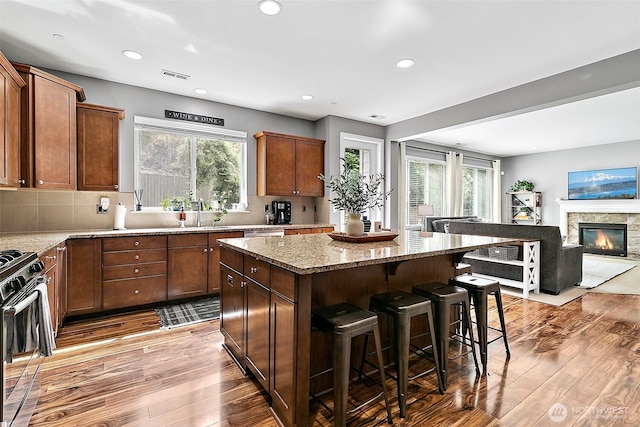 10508 174th Ave E, Bonney Lake, WA 98391 - kitchen with a kitchen island, gas range oven, wood finished floors, a kitchen breakfast bar, and light stone counters