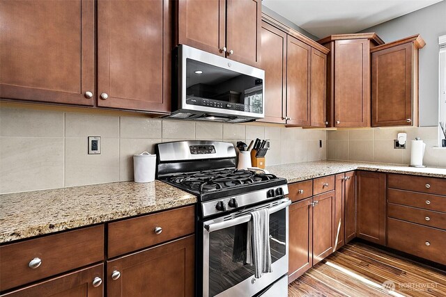 10508 174th Ave E, Bonney Lake, WA 98391 - kitchen featuring appliances with stainless steel finishes, light wood-style flooring, backsplash, and light stone counters