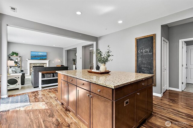 10508 174th Ave E, Bonney Lake, WA 98391 - kitchen featuring wood finished floors, a fireplace, light stone countertops, a center island, and recessed lighting