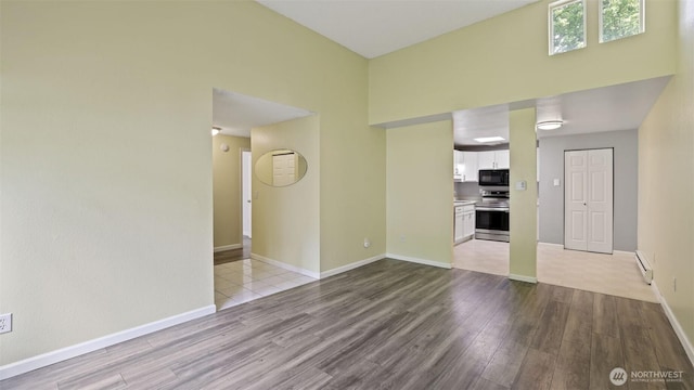 14600 SE 176th St Unit V1, Renton, WA 98058 - unfurnished living room with wood finished floors, baseboards, a high ceiling, and baseboard heating