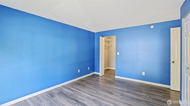 14600 SE 176th St Unit V1, Renton, WA 98058 - unfurnished bedroom with wood finished floors, a textured ceiling, baseboards, a closet, and a walk in closet