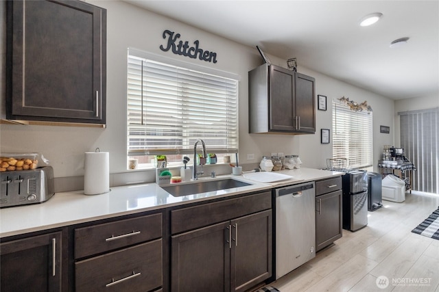 15028 Iverson Loop SE, Yelm, WA 98597 - kitchen featuring stainless steel dishwasher, a sink, dark brown cabinetry, light countertops, and light wood-style floors