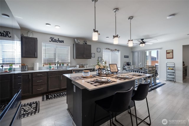 15028 Iverson Loop SE, Yelm, WA 98597 - kitchen featuring a sink, light wood-type flooring, a breakfast bar area, ceiling fan, and light countertops