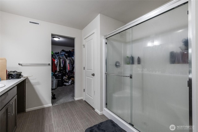 15028 Iverson Loop SE, Yelm, WA 98597 - bathroom with vanity, a shower stall, a walk in closet, and baseboards