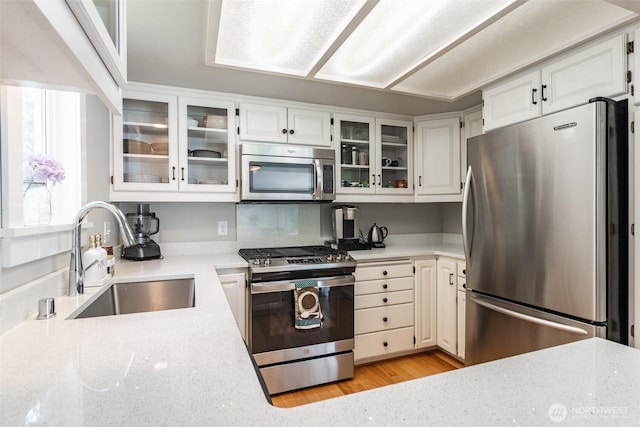 2 Greene Point Rd, Bellingham, WA 98229 - kitchen with appliances with stainless steel finishes, a sink, white cabinetry, light stone counters, and glass insert cabinets