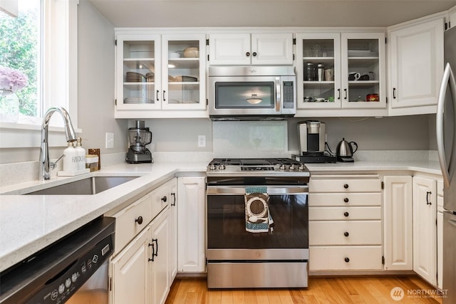 2 Greene Point Rd, Bellingham, WA 98229 - kitchen with stainless steel appliances, a sink, white cabinets, glass insert cabinets, and light wood finished floors