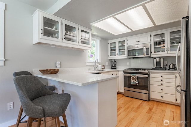 2 Greene Point Rd, Bellingham, WA 98229 - kitchen with stainless steel appliances, a peninsula, a sink, light wood-style floors, and white cabinetry