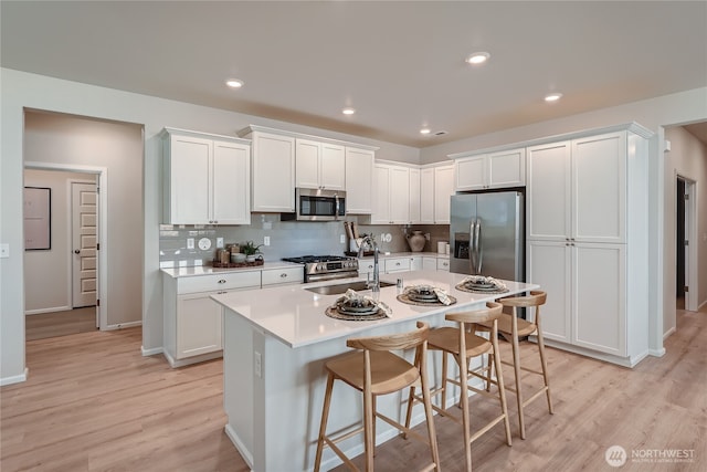 13461 192nd St E, Graham, WA 98338 - kitchen with stainless steel appliances, a sink, light wood-style flooring, light countertops, and a breakfast bar area