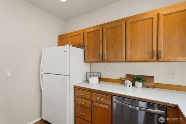 212 27th Ave E, Seattle, WA 98112 - kitchen with stainless steel dishwasher, freestanding refrigerator, light countertops, and brown cabinets
