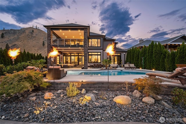 106 Shypoke Pl, Entiat, WA 98822 - back of property at dusk with an outdoor hangout area, a balcony, an outdoor pool, and a patio area