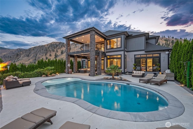 106 Shypoke Pl, Entiat, WA 98822 - back of property at dusk with outdoor lounge area, a balcony, a patio, an outdoor pool, and a mountain view