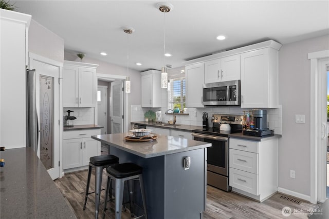 207 Moon River Vw SW, Mattawa, WA 99349 - kitchen featuring stainless steel appliances, a sink, wood finished floors, tasteful backsplash, and a center island