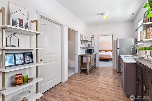 1080 Sunset Ln, Chelan, WA 98816 - kitchen with open shelves, light wood-type flooring, dark brown cabinets, a sink, and light countertops