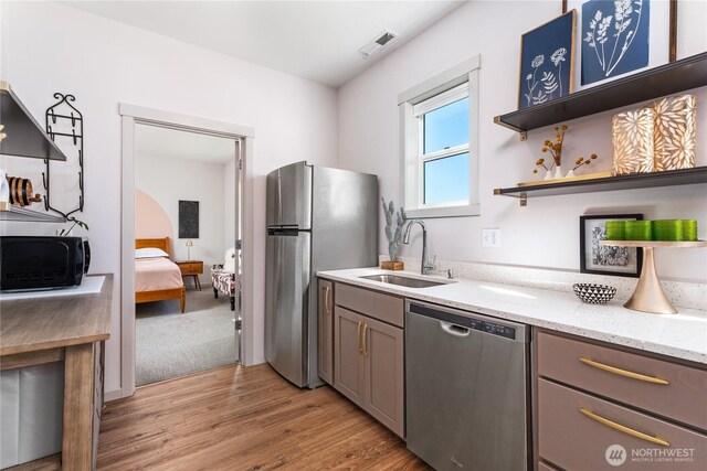 1080 Sunset Ln, Chelan, WA 98816 - kitchen featuring appliances with stainless steel finishes, a sink, light stone counters, light wood-style flooring, and open shelves