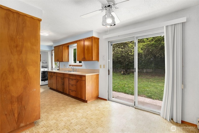 1642 Browns Point Blvd, Tacoma, WA 98422 - kitchen with light countertops, a sink, washer / dryer, brown cabinets, and ceiling fan