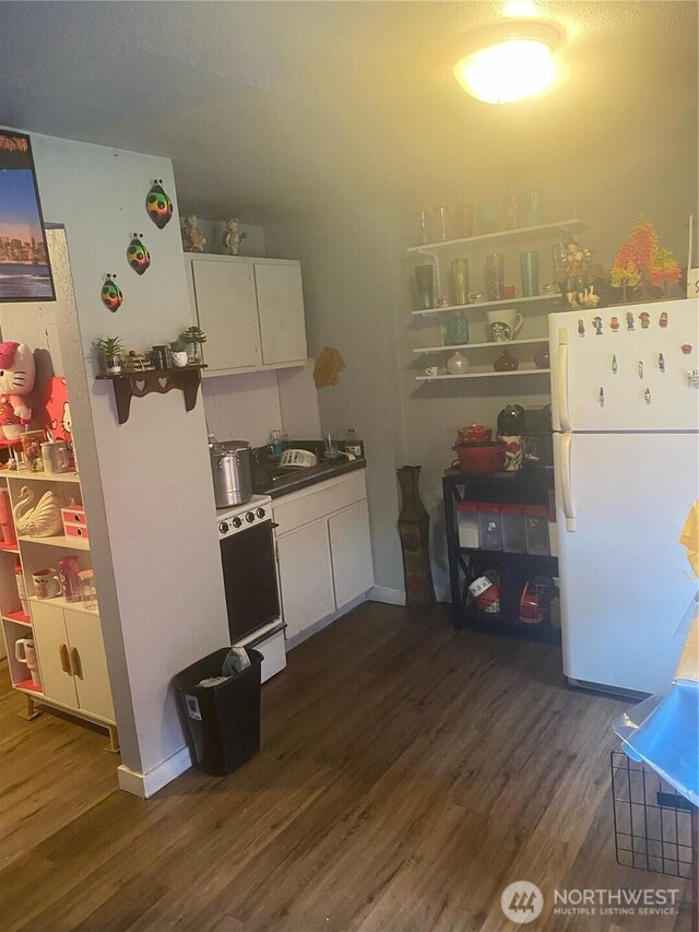 8040 Pacific Ave, Tacoma, WA 98408 - kitchen with freestanding refrigerator, range, dark wood-style floors, and white cabinetry