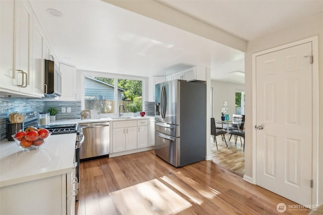 7309 134th Ave NE, Redmond, WA 98052 - kitchen with stainless steel appliances, a sink, decorative backsplash, white cabinets, and light wood finished floors