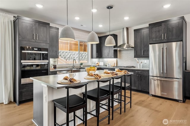 15310 204th Ave E Unit 22, Bonney Lake, WA 98391 - kitchen featuring appliances with stainless steel finishes, wall chimney range hood, a sink, light wood finished floors, and a kitchen bar