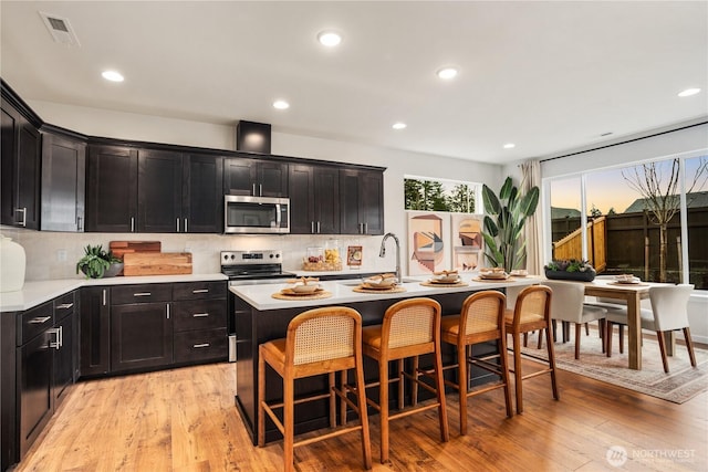 1192 68th Loop SE, Tumwater, WA 98501 - kitchen featuring stainless steel microwave, a kitchen breakfast bar, light wood finished floors, a sink, and recessed lighting