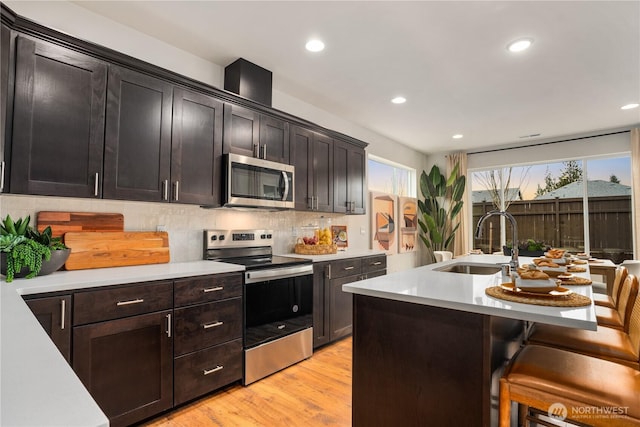 1192 68th Loop SE, Tumwater, WA 98501 - kitchen with appliances with stainless steel finishes, a sink, a breakfast bar area, light countertops, and recessed lighting