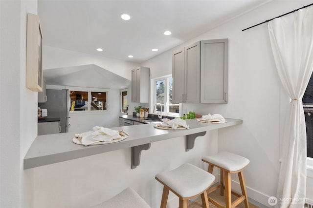 4642 Eastern Ave N, Seattle, WA 98103 - kitchen featuring gray cabinetry, freestanding refrigerator, a kitchen bar, recessed lighting, and light countertops
