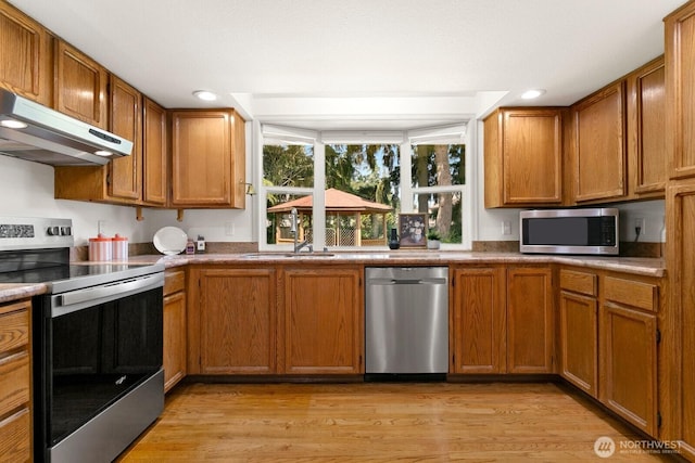 29617 58th Pl S, Auburn, WA 98001 - kitchen with stainless steel appliances, under cabinet range hood, light wood-type flooring, brown cabinets, and recessed lighting
