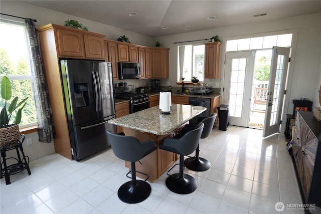 21266 Lafayette Rd, Sedro Woolley, WA 98284 - kitchen featuring stainless steel appliances, light stone countertops, a center island, a kitchen breakfast bar, and brown cabinetry