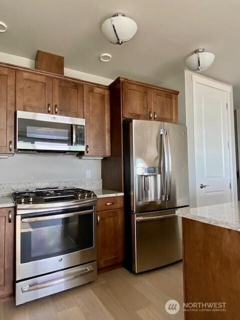 5105 Grand Loop Unit 107, Tacoma, WA 98407 - kitchen with appliances with stainless steel finishes, brown cabinetry, and light stone countertops