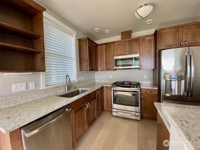 5105 Grand Loop Unit 107, Tacoma, WA 98407 - kitchen with appliances with stainless steel finishes, a sink, light wood-type flooring, and light stone counters