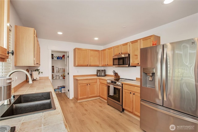 1860 Hoffman Hill Blvd, Dupont, WA 98327 - kitchen with stainless steel appliances, a sink, light brown cabinetry, light wood finished floors, and recessed lighting
