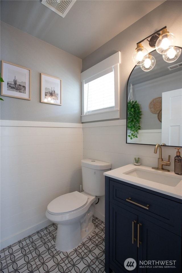 1860 Hoffman Hill Blvd, Dupont, WA 98327 - half bathroom with vanity, toilet, tile walls, a wainscoted wall, and tile patterned floors