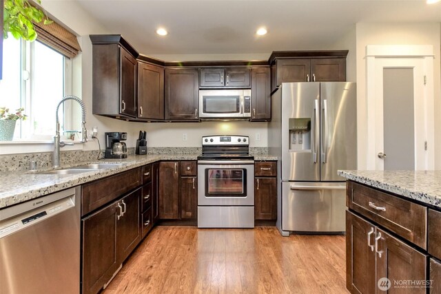 181 Coal Ave, Carbonado, WA 98323 - kitchen featuring stainless steel appliances, a sink, light wood finished floors, dark brown cabinets, and light stone countertops