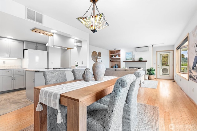 912 11th Unit 101, Bellingham, WA 98225 - dining space featuring a wall mounted air conditioner, light wood-type flooring, a fireplace, and built in features