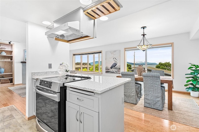 912 11th Unit 101, Bellingham, WA 98225 - kitchen featuring stainless steel range with electric cooktop, ventilation hood, light stone countertops, a peninsula, and decorative light fixtures