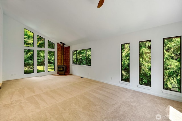 726 114th St NE, Tulalip, WA 98271 - carpeted spare room with a wood stove, vaulted ceiling, and a ceiling fan