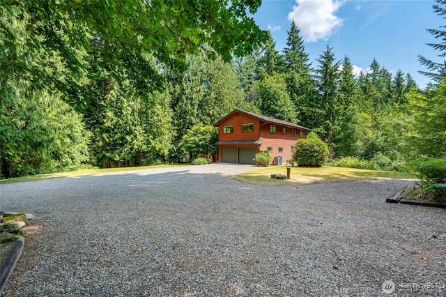 726 114th St NE, Tulalip, WA 98271 - view of front facade featuring a garage, gravel driveway, and a forest view