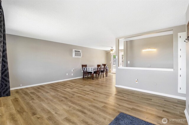907 S Balsam St, Moses Lake, WA 98837 - living room featuring a wall unit AC, ceiling fan, wood finished floors, baseboards, and a textured ceiling