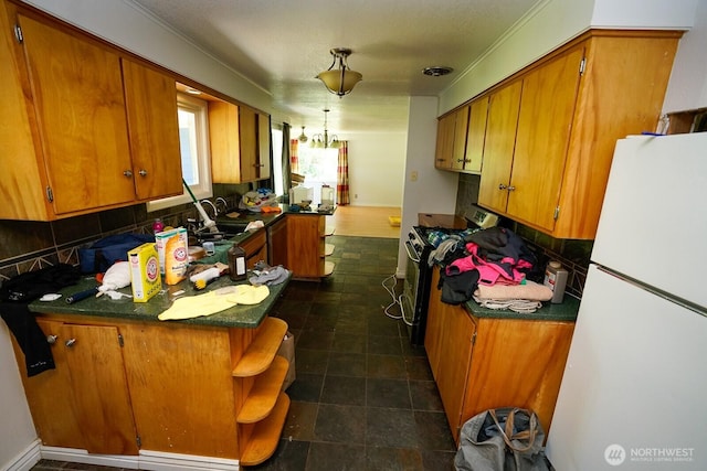 1245 W Axton Rd, Ferndale, WA 98248 - kitchen featuring freestanding refrigerator, a peninsula, range with gas stovetop, brown cabinets, and ornamental molding