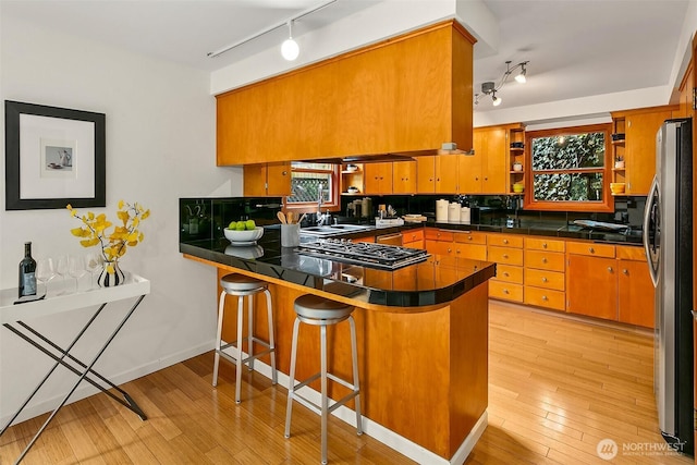 718 N 59th St, Seattle, WA 98103 - kitchen with rail lighting, a peninsula, stainless steel appliances, open shelves, and light wood-style flooring