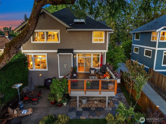 5613 21st Ave SW, Seattle, WA 98106 - back of property at dusk featuring a shingled roof, a patio, an outdoor living space, and a deck